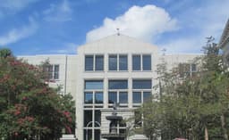 Exterior of the J. Waties Waring Judicial Center, the federal courthouse in Charleston, South Carolina, a modern limestone building with tall windows and a fountain in its forecourt, its facade engraved 'Hollings Judicial Center'