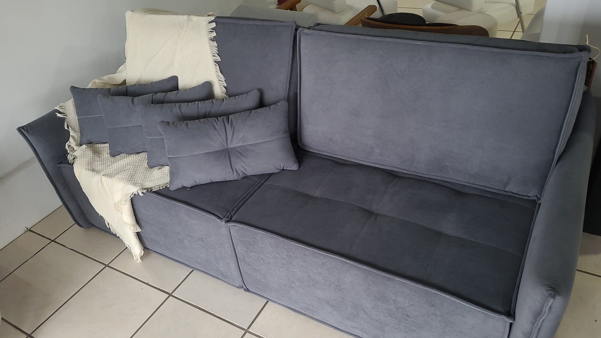 A generic gray upholstered sofa with throw pillows in a furniture showroom — a representative file photo of living-room furniture, not the recalled Joy Furniture Talan or Royce reclining sets