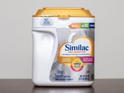 A container of Similac infant formula on a wood surface