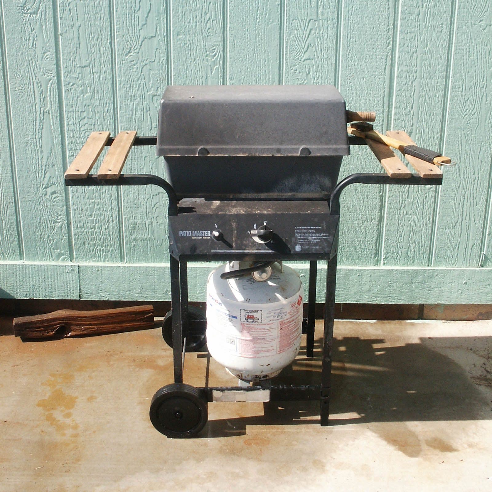 A standard single-burner propane gas grill with visible cooking grate — grill brushes used to clean such grates are the subject of the Nexgrill recall