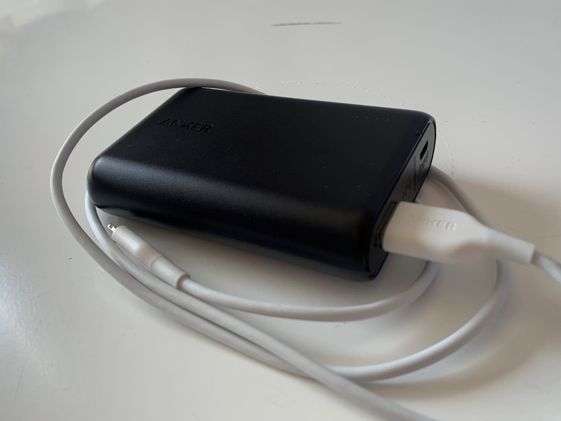 Black lithium-ion portable power bank with a charging cable on a plain surface, representing the category behind the 2025 recall surge