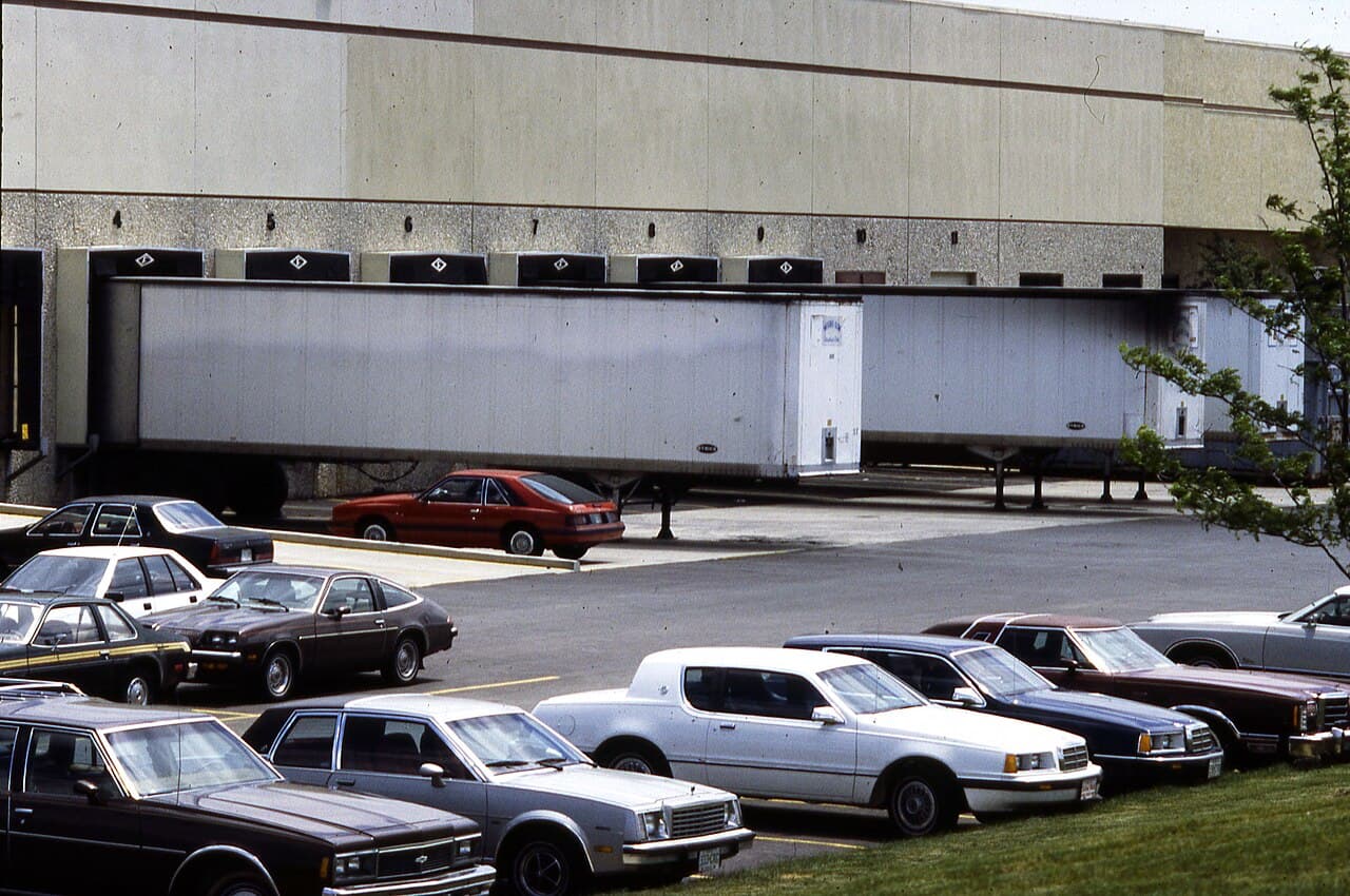 A tractor-trailer backed into a row of warehouse loading-dock doors, with an empty truck bay alongside.